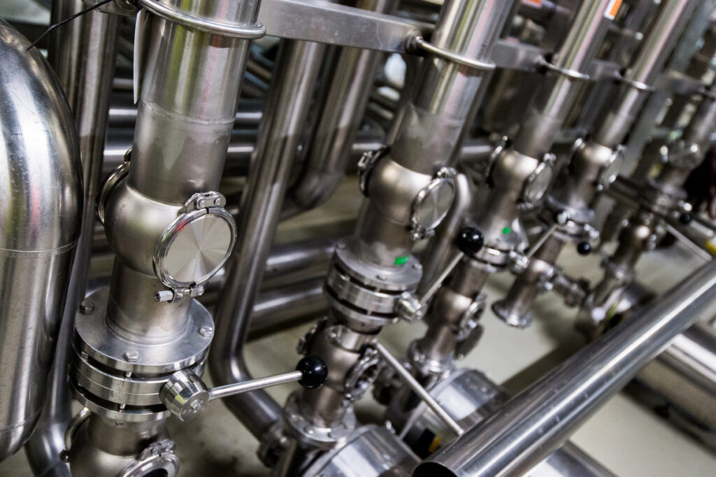 Close-up view of industrial stainless steel valves and pipes in a manufacturing facility.